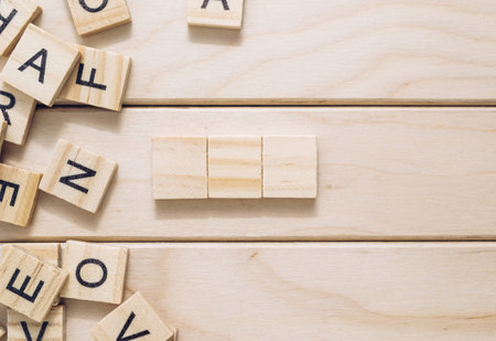 Wooden board with a few letters and a block of wood on it. The block of wood is placed in the middle of the lettersの写真素材