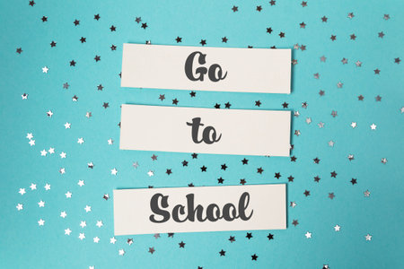 Blue background with a white sign that says Go to School. The sign is placed on top of a pile of...