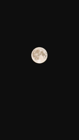 Bright full moon illuminates the dark night sky, revealing intricate surface textures and craters,...