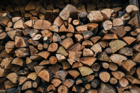 Stacked logs of firewood in a rustic display, featuring diverse sizes and textures, perfect for cozy...