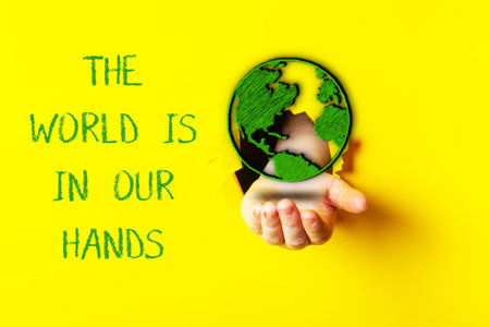 A hand cradles a green globe representing our duty to protect the environment, set against a bright...