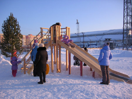 Russia, Novosibirsk, January 15, 2012: cheerful children with their parents ride with an ice wooden slide in the Park in winter walkのeditorial素材