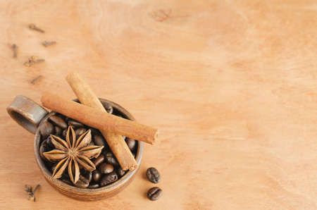 Cup with coffee beans, cinnamon sticks and star anise on a wooden table. Selective focus. Copy space.の写真素材
