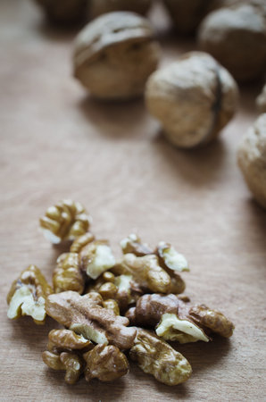 Walnut kernels and whole walnuts on rustic old wooden table. Rustic style.