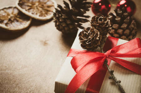 Vintage Christmas background. Kraft boxes with gifts, tied with red ribbons and pine cones in rustic style. Selective Focus. Copy space.の写真素材