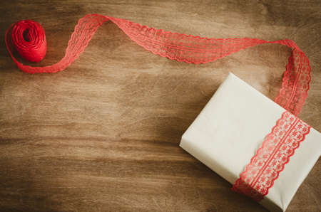 Vintage kraft boxe with gift, tied with red ribbon on rustic wooden background. View from above with copy space.の写真素材