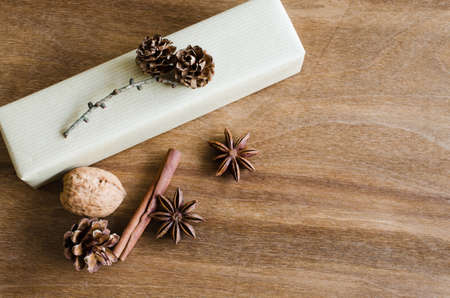 Vintage Christmas Kraft Gift Box in Rustic Style Decorated with Pine Cones and Cinnamon on Wooden Background. View from above with copy space.の写真素材