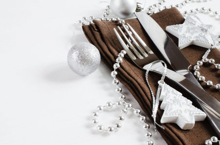 Christmas table setting from above. Cutlery on linen napkin with christmas silver decorations on...