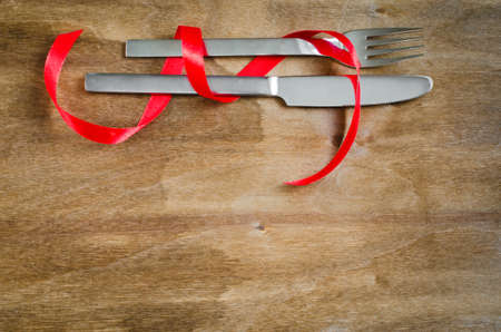 Cutlery Decorated with Red Ribbon on Wooden Background. Selective Focus. Space for Text.の写真素材
