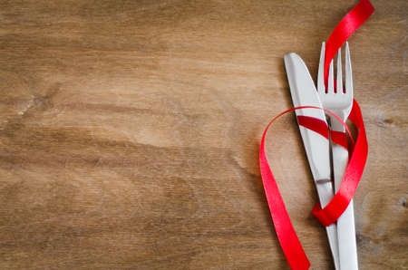 Cutlery Decorated with Red Ribbon on Wooden Background. Selective Focus. Space for Text.の写真素材