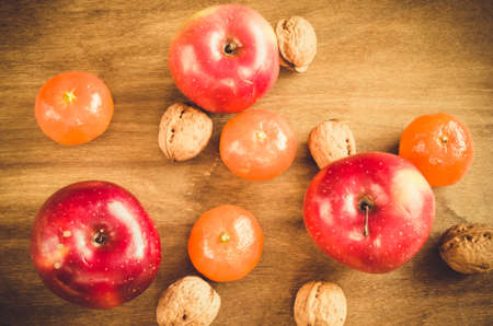 Organic apples, tangerines and walnuts on a wooden background. Selective Focus. Rustic style. Toned image.の写真素材