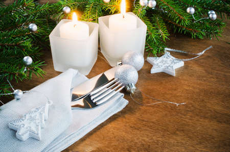Table Place Setting for Christmas Eve. Winter Holydays. Christmas background. Cutlery on napkin, candles and fir branches on rustic wooden background. Selective focus, space for text.の写真素材