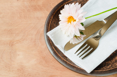 Rustic table setting with fresh flower, napkin and silverware. Space for text. Top view. Selective...