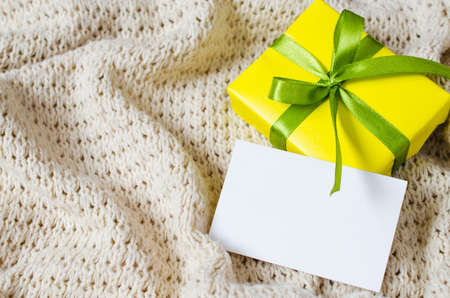 Present With Empty Postcard on Beige Knitted blanket background. Selective focus.の写真素材