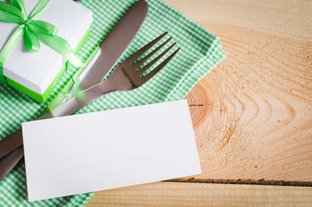 Dining Table Setting. Cutlery with Empty Tag and Present on Linen Napkin on Rustic Wooden Background. Spring Concept. Copy Space. Selective Focus.の写真素材