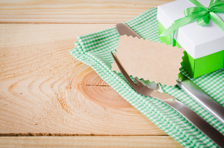 Dining Table Setting. Cutlery with Empty Tag and Present on Linen Napkin on Rustic Wooden Background. Spring Concept. Copy Space. Selective Focus.の写真素材