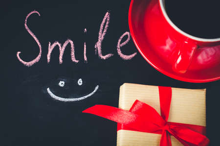 Cup of Coffee and Present on a Dark Background. Inscription Smile. Toned Image. Selective Focus. Top View.の写真素材