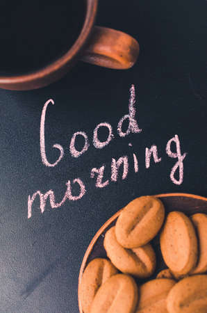 Cup of Coffee and Cookie or Biscuit on a Dark Background. Inscription Good Morning. Toned Image. Selective Focus. Top View.の写真素材