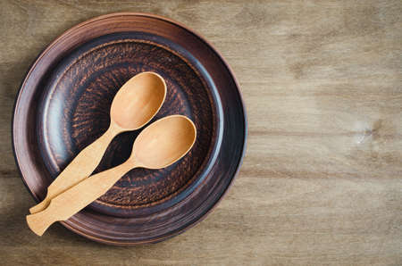 Rustic Kitchen Utensils: the Ceramic Plates and Wooden Cutlery on Wooden Background. Home Wares. Kitchen Decor in Rustic Style. View From Above With Copy Space.の写真素材