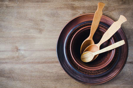 Rustic Kitchen Utensils: the Ceramic Plates and Wooden Cutlery on Wooden Background. Home Wares. Kitchen Decor in Rustic Style. View From Above With Copy Space.の写真素材