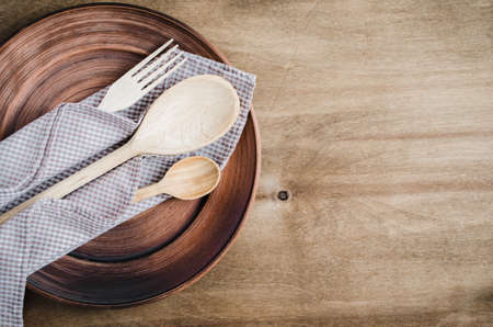Rustic Kitchen Utensils: the Ceramic Plates and Wooden Cutlery on Wooden Background. Home Wares. Kitchen Decor in Rustic Style. View From Above With Copy Space.の写真素材
