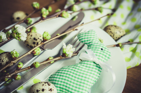 Festive table setting for Easter dinner with spring flowers and cutlery on wooden rustic table....