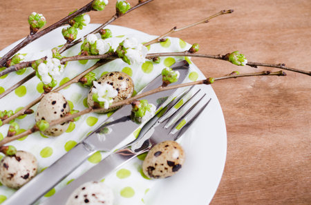 Festive table setting for Easter dinner with spring flowers and cutlery on wooden rustic table....