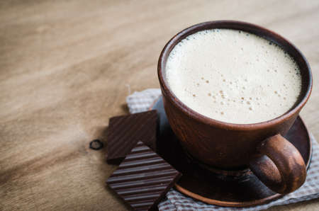 Cup of Cappuccino With a Piece of Chocolate on Wooden Background. Rustic Style. Selective Focus.の写真素材