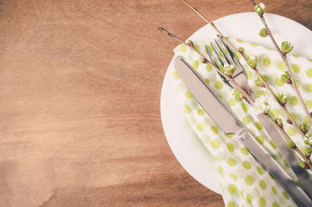 Spring Festive Table Setting with Flowering Branch Cherries, Cutlery and Napkin on Wooden Rustic Table. Selective Focus.の写真素材
