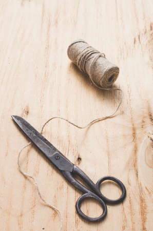 Old scissors and skein jute twine on a wooden background. Rustic style. Selective focus.の写真素材