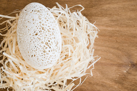 Table Setting for Easter Celebration. Carved Egg in the Nest on Wooden Background. Holidays...