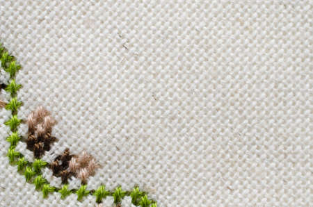 Handmade Embroidery by Cross Stitch in the View of Acorns. Texture of Beige Natural Linen Fabric with Embroidery for Background.の写真素材