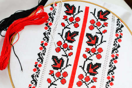 The wooden hoop with the embroidery pattern of red and Black color on canvas. Slavic Embroidery with hemming.の写真素材