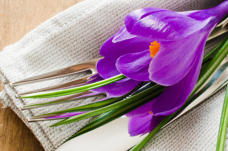 Spring festive table setting with plate napkin and cutlery on wooden table