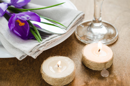 Spring Festive Table Setting With Fresh Flower and Candles. Napkin, plate and cutlery on wooden...