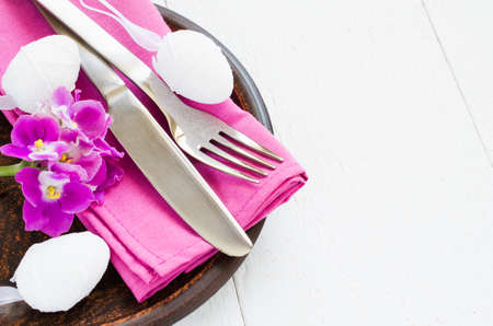 Easter Festive Table Setting With Fresh Flower. Napkin, plate and cutlery on wooden table. Holidays background. Selective Focus.の写真素材