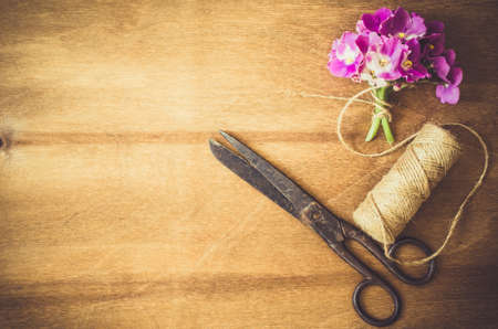 Vintage floristic background, bouquet fresh cut flowers, antique scissors and a rope on wooden table. Selective Focus. Copy Space.の写真素材