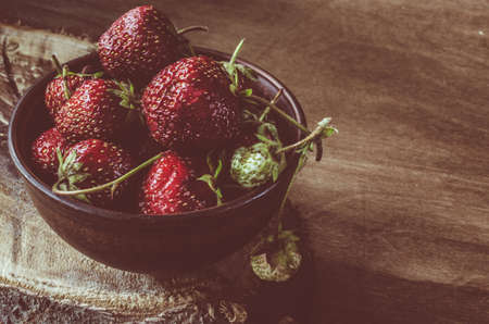 Fresh ripe organic strawberry on wooden background. Vintage rustic style and color tinting. Selective focus.の写真素材