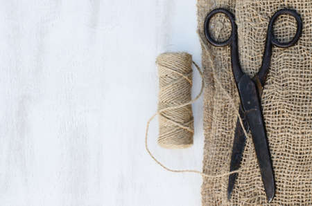 Old scissors, skein jute twine and burlap on a wooden background. Rustic style. Selective focus.の写真素材