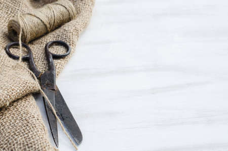 Old scissors, skein jute twine and burlap on a wooden background. Rustic style. Selective focus.の写真素材