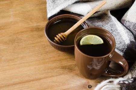 A cup of hot tea with lemon and honey, plaid on a rustic table. Cozy autumnal mood, warm autumn.の写真素材