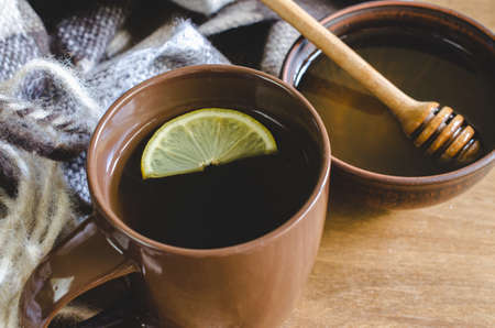 A cup of hot tea with lemon and honey, plaid on a rustic table. Cozy autumnal mood, warm autumn.の写真素材