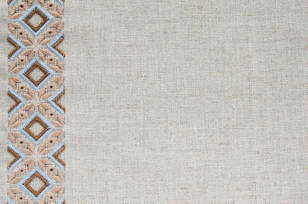 Embroidered fragment on flax by brown and beige cotton threads. Embroidery texture flat stitch. Ukrainian ethnic ornament.の写真素材