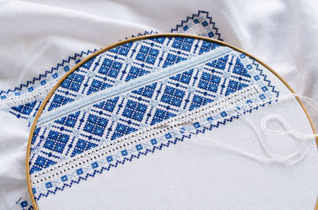 Embroidery hoop with fragment embroidered fabric. Design of ethnic pattern. Embroidery texture. Cross stitch.の写真素材