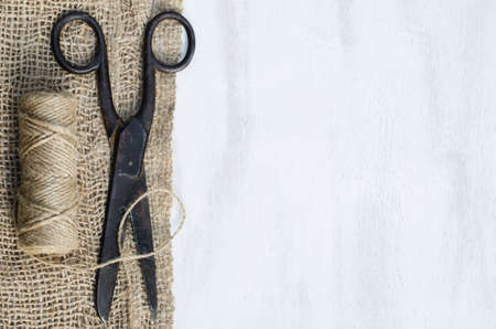 Old scissors, skein jute twine and burlap on a wooden background. Rustic style. Selective focus.の写真素材