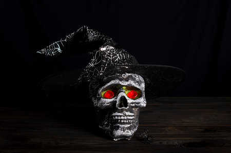 Halloween still-life background with decorative skull on a dark wooden table. copy space