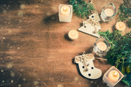 Christmas background with fir tree, burning candles and decoration on wooden board. Advent time. Snow effect. Toned image Copy Spaceの写真素材