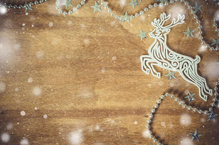 Christmas Background for Holiday Card in Rustic Style. Xmas Decorative Deer on Wooden Board. Copy Space for Your Text. Toned image. Snow effect.の写真素材