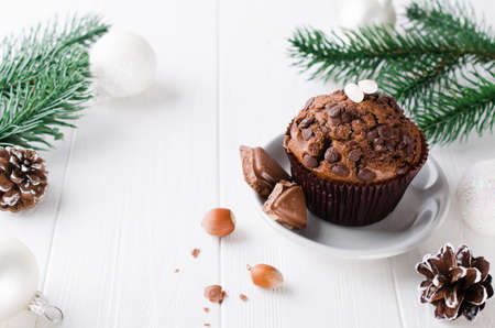 Chocolate muffin and branches fir on white wooden background. Selective Focus. Copy space.の写真素材
