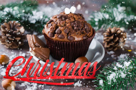 Chocolate muffin, branches fir and Merry Christmas inscription. Xmas time. Snow effect. Selective Focus. Copy space.の写真素材